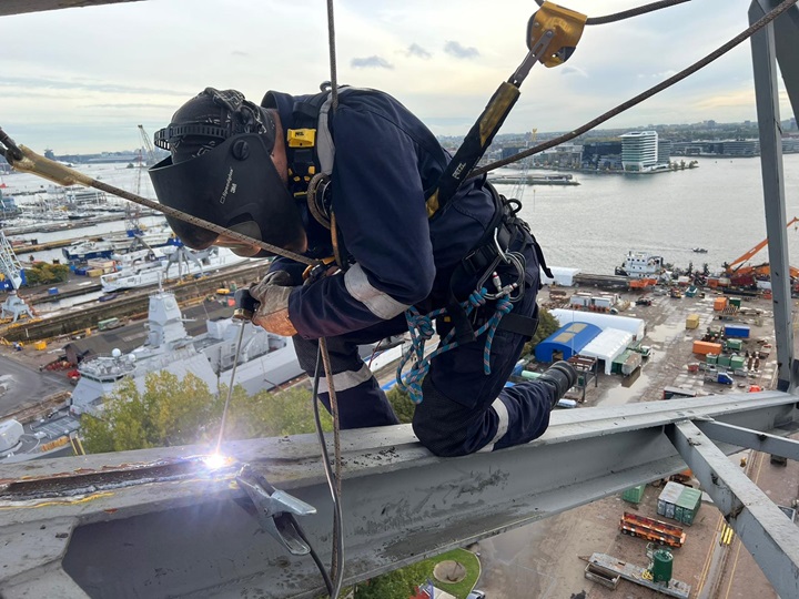 Rope access specialist voert laswerk uit op grote hoogte