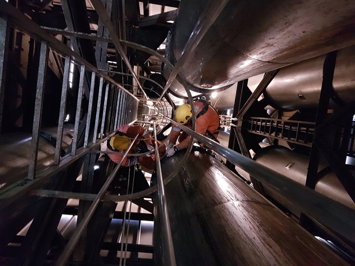 Rope access specialist voert montagewerk uit in een moeilijk toegankelijke, besloten ruimte op hoogte